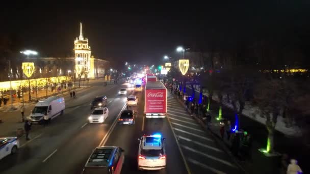 コーラ車の新年キャラバンが道路に沿って旅行しています 人は出会い ガーランドには背の高いクリスマスツリーがあり 照明や装飾が周りに輝いています 2022年12月28日 — ストック動画