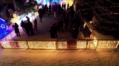 Noel ve yeni yıl için çok güzel dekore edilmiş bir ev. Kar yağıyor, Noel ağaçlarındaki çelenkler parlıyor, bir atlıkarınca, çeşitli dekorasyonlar, toplar ve oyuncaklar. İnsanlar yürüyor. Üst Manzara. Almaty