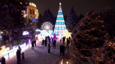 Noel ve yeni yıl için çok güzel dekore edilmiş bir ev. Kar yağıyor, Noel ağaçlarındaki çelenkler parlıyor, bir atlıkarınca, çeşitli dekorasyonlar, toplar ve oyuncaklar. İnsanlar yürüyor. Üst Manzara. Almaty