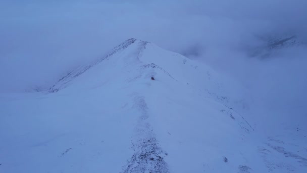 云中的高山上的一个救援小屋 有一个登山者站在房子旁边 白云笼罩着雪山 黄色的黎明和乌云 石头躺着 阿拉木图 — 图库视频影像