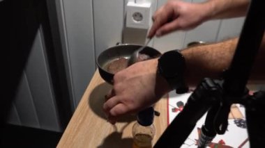 Two steaks are fried in a frying pan on a gas burner. Horse meat is being prepared. Steaks in butter. Cooking on a hike, in a rescue hut. The mans hand turns over the meat. Gas cylinder and table