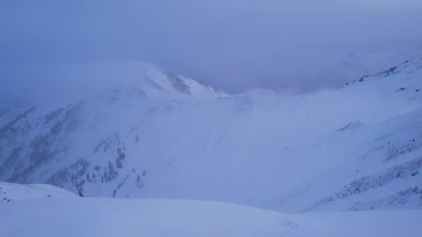 雲の間の山の中で救助小屋高 家の隣には登山家が立っている 白い雲が雪の山に包まれた 黄色の夜明けと雲 雪の丘 2023 Almaty — ストック動画