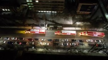 Red trucks with Coca Cola are passing through the city. Aerial view from a drone on a caravan of cars. Red cars with yellow lights are driving on the road. Lights are shining. Almaty December 28, 2022
