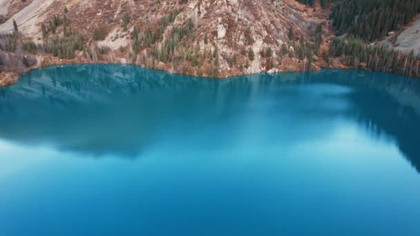 高山湖水的镜面映衬着秋天的高山和针叶树 乌云和天空透过碧绿的海水 带着蓝色的阴影 清晰可见 伊塞克山湖 — 图库视频影像