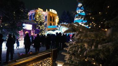 Sokaktaki insanlar yeni yılı ve Noel 'i kutluyorlar. Yumuşak kar yağıyor. Güzel parlak süslemeler neon ışıklarla parıldıyor. Tüm çitler çelenklidir. Bir Noel ağacı ve güzel bir ev