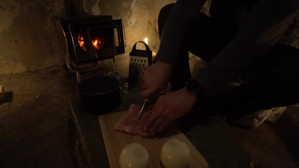 他们在一个古老的小屋里切肉 那些人在做饭 桌上有一个洋葱 一个平底锅和一个土拨鼠 用肉创造了一个农场 营房的火炉里正在燃着蜡烛和火 不同寻常的气氛 — 图库视频影像