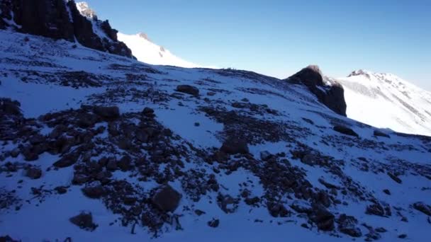 Group People Walking Snowy Mountains Huge Stones Covered Snow Blue — Vídeo de Stock