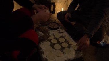 Eski bir kulübede yemek pişirmek. Hamur köftesi yapıyorlar. Terk edilmiş bir kulübede sıcak bir atmosfer. Kamp ocağında ateş ve mumlar var. Turistler kamp masasında hamur tatlısı yaparlar. Kızartma tavasında kıyma.