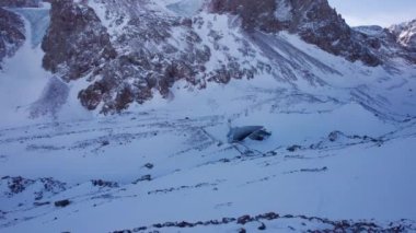 Dağlardaki bir buzuldan dev bir buz duvarı. Her yer kar ve büyük taşlarla kaplı. Buzdaki çatlaklardaki dronun üst görüntüsü. Buzul kırılır, buz kırılır. Almaty