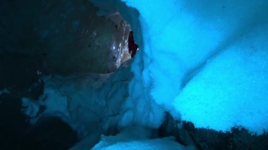 Bir turist karla kaplı bir buz mağarasına girer. Adamın ağzından buhar fışkırıyor. Mavi tonlu beyaz kar, gri buzullu buz. Büyük taşlar. Uzaktan bir ışık görünüyor. El feneri.