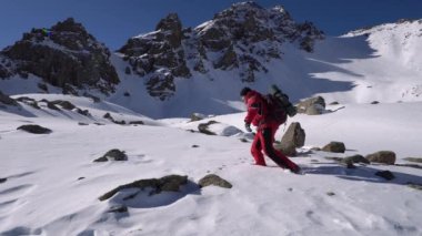 Injured his leg while climbing in the mountains. A guy with a big backpack fell through the snow and hit his foot. I fell into a snowdrift from the pain. Blue sky, high snowy mountains. Survival