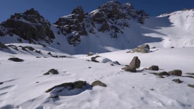 Snowy mountains with ancient glaciers and rocks. Steep cliffs with large rocks. Everything is covered with a huge layer of white snow. Clear blue sky and the sun is shining brightly. A place to climb