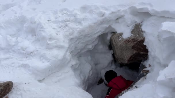 Wspinacz Plecakiem Schodzi Lodowej Jaskini Dziurze Duże Kamienie Biały Śnieg — Wideo stockowe