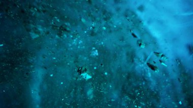 Turquoise pure color of ice inside the ice cave. Stones and icicles are visible in places. Light grains of snow on the ice walls. Frozen air bubbles in an ice wall. An ancient glacier. Color gradient