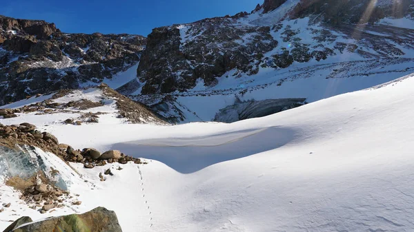 多雪的高山 阳光灿烂 岩石斑斓 苔藓生长在巨石之上的地方 蓝冰破雪而出 雪下的冰川 一个登山者的灵魂和身体安息的地方 — 图库照片