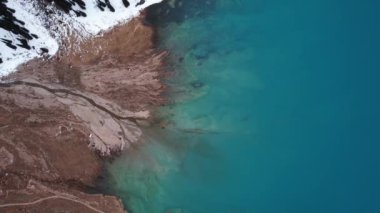 Dağlarda turkuaz mavi suyu olan bir göl. Temiz su, kozalaklı ağaçlar ve karlı dağlar. İnsanlar kıyı boyunca yürür, alçak çalılar büyür. Büyük Almaty Gölü. Kazakistan