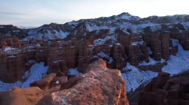 Turuncu kaya duvarlı Charyn Grand Canyon. Dik kanyon duvarlarının, çatlakların ve tünellerin insansız hava aracı görüntüsü. Bazı yerlerde kar var. Güneş ışıl ışıl parlıyor. Büyük Kanyon 'un kardeşi.