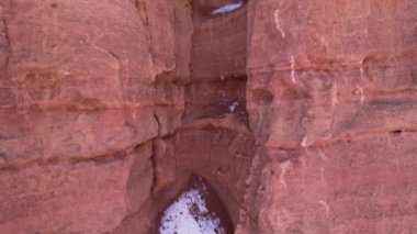 Turuncu kaya duvarlı Charyn Grand Canyon. Dik kanyon duvarlarının, çatlakların ve tünellerin insansız hava aracı görüntüsü. Bazı yerlerde kar var. Güneş ışıl ışıl parlıyor. Büyük Kanyon 'un kardeşi.