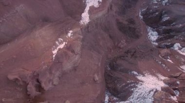 Turuncu kaya duvarlı Charyn Grand Canyon. Dik kanyon duvarlarının, çatlakların ve tünellerin insansız hava aracı görüntüsü. Bazı yerlerde kar var. Güneş ışıl ışıl parlıyor. Büyük Kanyon 'un kardeşi.