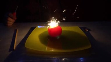 Parlayan bir domatesin içinde yanan bir maytap. Tabaktaki sebzelerle deney yap. Yangından kıvılcımlar farklı yönlere uçar, domates karanlıkta parlamaya başlar. Muhteşem bir elma gibi.