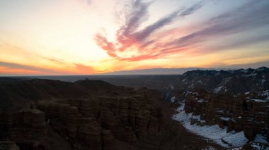 Turuncu kaya duvarlı Charyn Grand Canyon. Dik kanyon duvarlarının, çatlakların ve tünellerin insansız hava aracı görüntüsü. Bazı yerlerde kar var. Güzel gün batımı ve gün doğumu. Büyük Kanyon 'un kardeşi.