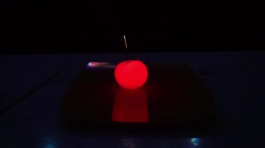 Parlayan bir domatesin içinde yanan bir maytap. Tabaktaki sebzelerle deney yap. Yangından kıvılcımlar farklı yönlere uçar, domates karanlıkta parlamaya başlar. Muhteşem bir elma gibi.