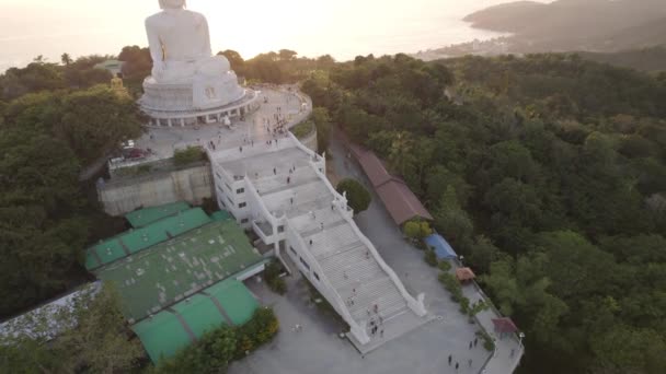 从无人机看到日落时的大佛 人们爬上台阶爬上雕像 岛上的青山到处都是 在远方 明亮的太阳掠过大海 从上面看 — 图库视频影像
