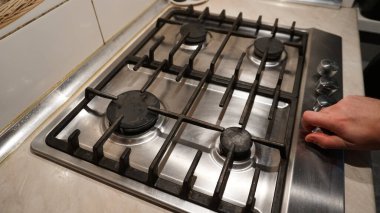 Ocağın gazını kapat ya da aç. Siyah ocak üzerinde mavi ateş alevi. Adam ya gazı kapatır ya da açar. Çelik tabakta siyah ızgara. Duvarlarda beyaz fayanslar. Soğuk kış