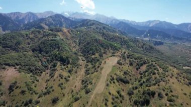 Dağların arka planındaki renkli parlak toplar gökyüzüne doğru uçuyor. Sarı, yeşil, kırmızı, mavi top daha da yükselecek. Yeşil vadi, karlı tepeler. Mavi gökyüzünde beyaz bulutlar var. Tatil