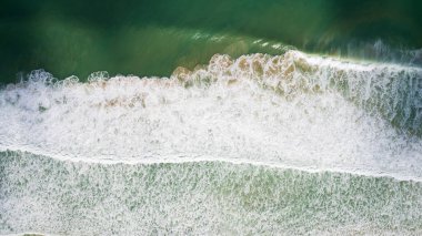 Fırtınalı okyanus manzarası ve bulutların gölgeleri. Dalgalar, denizin zümrüt rengini veren kahverengi kumu yükseltir. Beyaz köpük. Bulut gölgeleri karanlık bir eğilim yaratır..