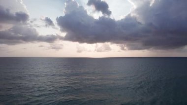 Deniz manzaralı ve bulutlu güzel bir gün batımı. Kumlu bir sahil ve su üzerindeki bir dronun üst görüntüsü. Turistler rahatlar ve yüzerler. Phuket Adası, Tayland 'ın yeşil tepeleri. Evler ve yüksek palmiye ağaçları