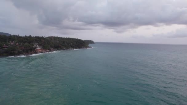 海の真ん中にある緑の島のトップビュー 雲から濃い緑色の水 波が島の岩に打ち寄せている チョッピー ドローンからの眺め プーケットのカロンビーチ — ストック動画