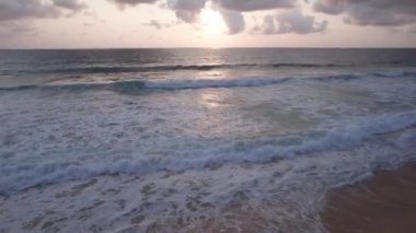 Deniz manzaralı ve bulutlu güzel bir gün batımı. Kumlu bir sahil ve su üzerindeki bir dronun üst görüntüsü. Turistler rahatlar ve yüzerler. Phuket Adası, Tayland 'ın yeşil tepeleri. Evler ve yüksek palmiye ağaçları