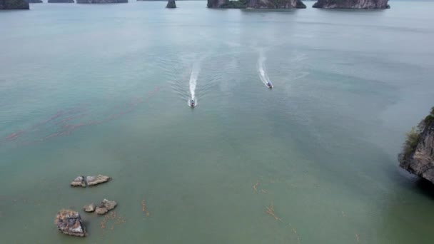 一艘泰国长尾船在张恩加岛之间航行 高大的石灰岩悬崖上覆盖着绿树 可以看到海滩和洞穴的地方 船上的游客 水面上的脚印 — 图库视频影像