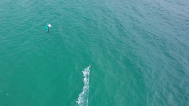 ある男が海の波に乗って キッズサーフィンに乗る グリーン透明な水 イエローサンド ドローンからパラグライダーまでトップビュー ボードは水面にスライドする プーケットの大きな緑の島 — ストック動画