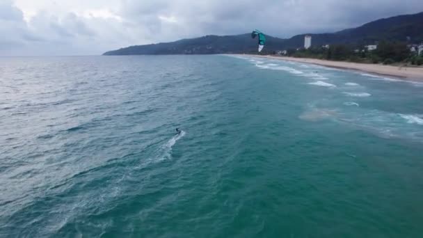 一个家伙骑在海浪上在风筝冲浪 绿色透明水 黄色的沙子从无人机到滑翔机的最高视图 木板在水面上滑行 普吉这个绿色的大岛 — 图库视频影像
