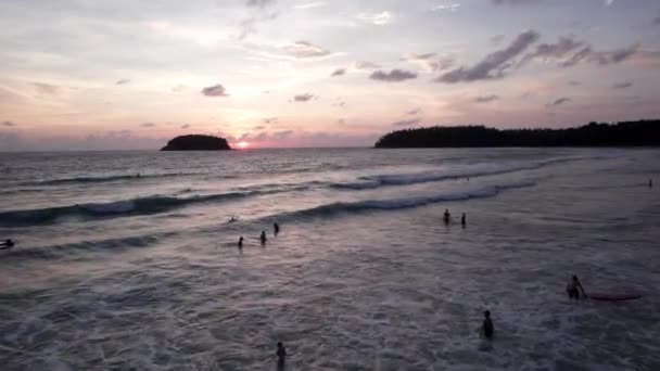 人々は島の景色で夕日を賞賛します 孤島は海の中にあり 波はその周りに曲がります 空にピンクの雲 人々が入浴し 太陽を見る タイのビーチホリデー — ストック動画