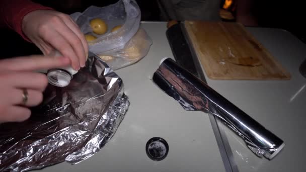 有盐的土豆用铝箔包裹在桌子上 准备土豆 在火上的煤块中结巴 野营桌上有铝箔 一袋土豆和一块刨花板 — 图库视频影像
