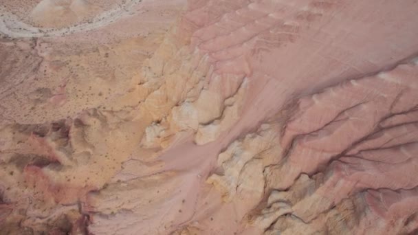 多彩的高山和由粘土制成的峡谷 一个有着不同岩石和不同颜色的大峡谷 岩石墙壁上的红色 白色和黄色的花 一个游客散步 Aktau — 图库视频影像