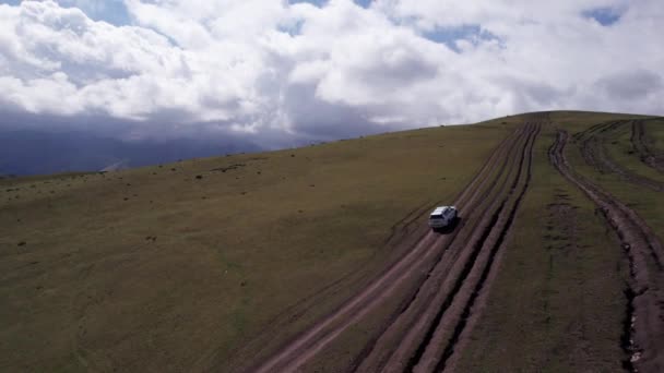 Suv는 산에서 운전하고 있습니다 거대한 산봉우리와 필드의 드론에서 더러운 오프로드와 — 비디오