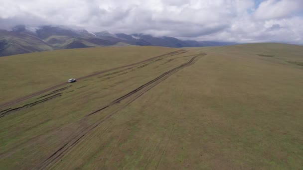 Bílé Suv Projíždí Horami Přes Pole Letecký Pohled Bezpilotního Letounu — Stock video