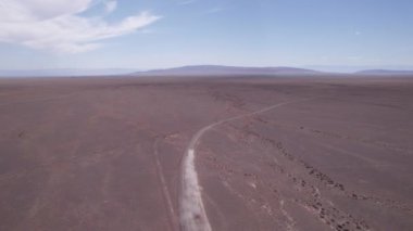 Bozkırda tozlu bir yolda beyaz bir SUV hızlı gidiyor. Tekerleklerin altından ve arabanın çatısından toz bulutları uçar. Cip toprak bir yolu kolayca geçer. Mavi gökyüzü ve beyaz bulutlar.
