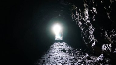 Islak mağaranın sonundaki ışık ve çıkış. Güneş ışınları taştan nemli duvarlara düşer. Dağda yapay bir mağara. Video kapısına bir geçit yapıldı. Tünelin sonundaki parlak ışık