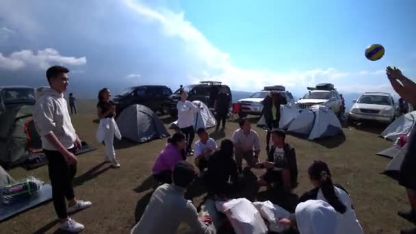 自然の中でボールで遊ぶ人たち 円を形成し ボールを投げました テントキャンプと車がある 大きな雲と青い空 2022 アッシー プラトー カザフスタン — ストック動画