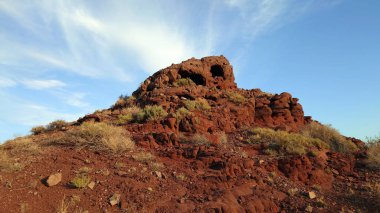 Volkanik bir yer. Donmuş eski lav. Kızıl Dağlar. Kaya kırmızı-kestane renginde, kayalarda mağaralar oluşmuş. Çimenler ve çalılar büyür. İnsansız hava aracının görüntüsü. Doğmamış bir volkan. Kazakistan.