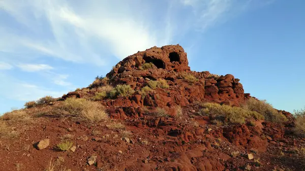 Volkanik bir yer. Donmuş eski lav. Kızıl Dağlar. Kaya kırmızı-kestane renginde, kayalarda mağaralar oluşmuş. Çimenler ve çalılar büyür. İnsansız hava aracının görüntüsü. Doğmamış bir volkan. Kazakistan.