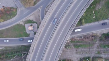 Şehirden geçen köprünün drone görüntüsü. Arabalardan kamyonlara farklı arabalar geçiyor. Serbest şerit. Gün batımında sisli bir şehrin arka planına karşı. Fabrikanın bacaları tütüyor.