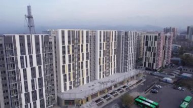 Yol kenarında yüksek evler inşa ediliyor. Almaty şehri. Yeni çok katlı binalar inşa ediliyor. İnşaatçılar, vinç, makineler çalışıyor. İHA 'dan evlerin ve yolların havadan görüntüsü.