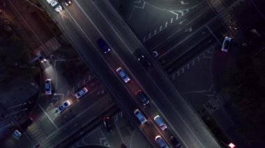 Bir sürü araba, otobüs ve kamyonla dolu yoğun bir kavşak. Gece yolundaki İHA 'nın, şehrin ve yayaların hava görüntüsü. Işıklar ve farlar parlıyor. Trafik sıkışıklığı oluştu. Almaty