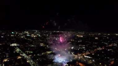 Şehir merkezindeki havai fişeklerden gelen büyük parlak ışıklar. Gece şehri Almaty 'deki bir İHA' nın hava görüntüsü, renkli ışıklar ve fenerler. İnsanlar dinleniyor. Arabalar geliyor. Şehirde bir tatil.